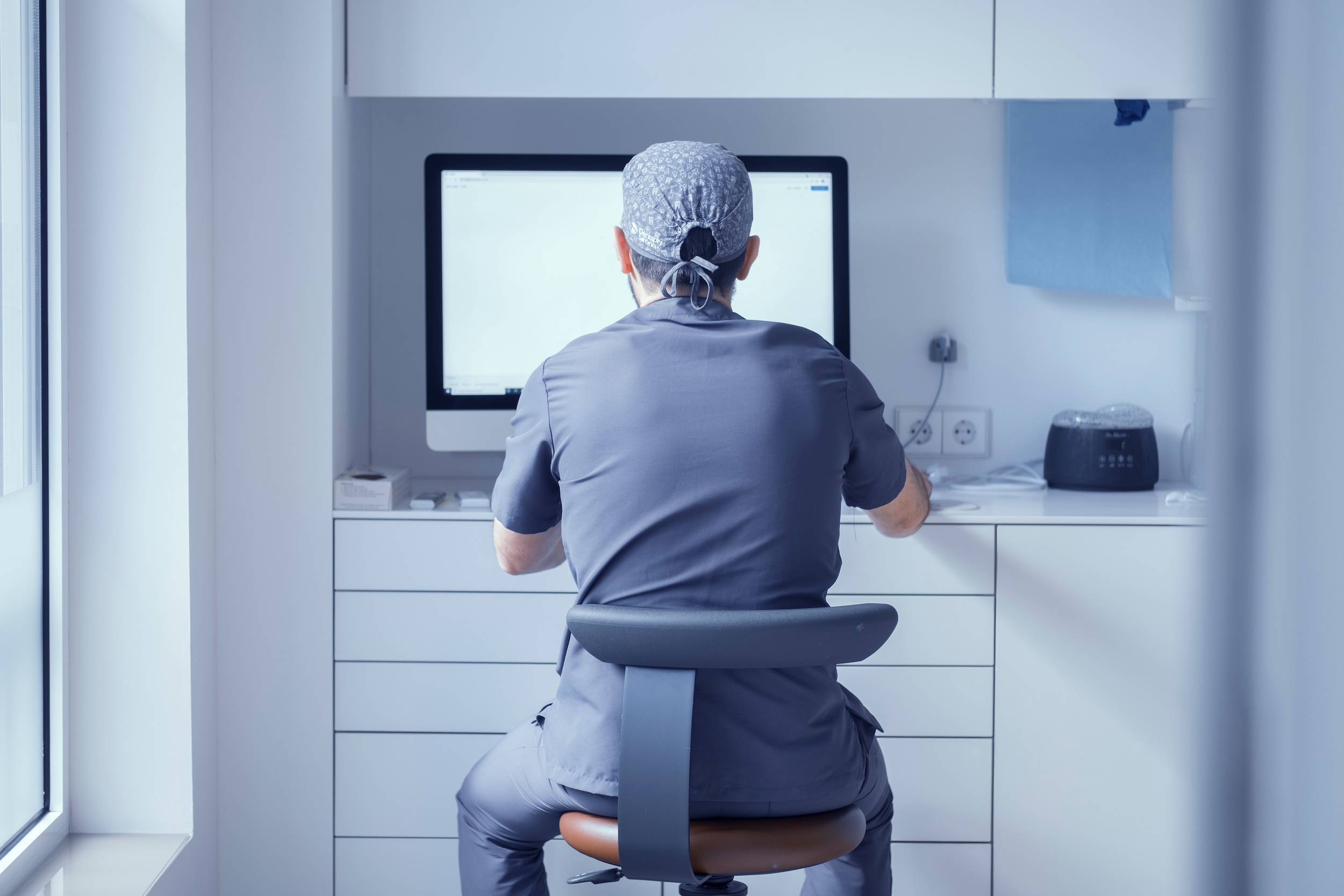 dentist sitting at computer learning how to write a professional bio for his dental website