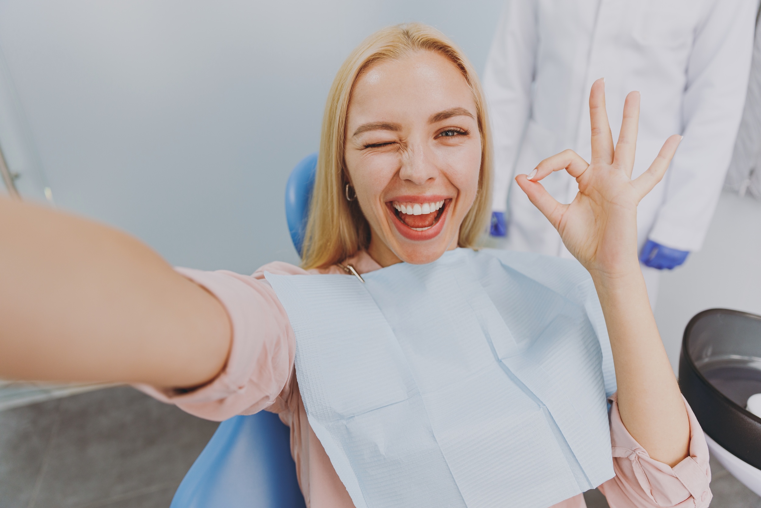 attractive young woman smiling and taking a selfie at the dental office shows the importance of positive experiences for dentists wanting to get more reviews for their dental practice